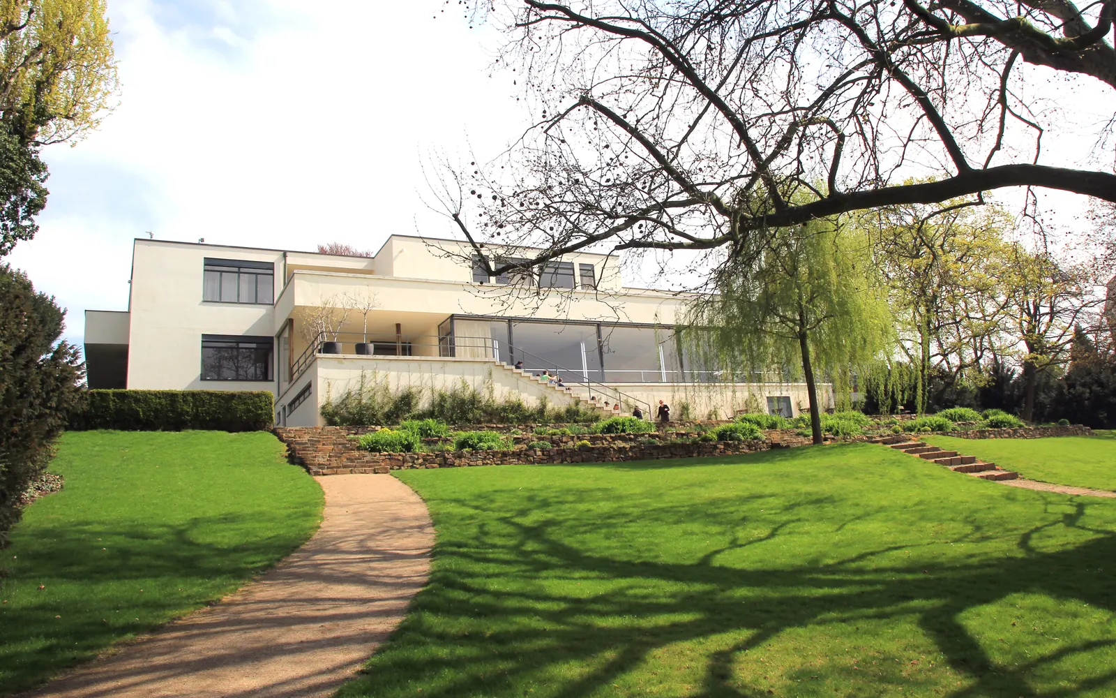 The garden façade of Villa Tugendhat above its sloping lawn and the curving path