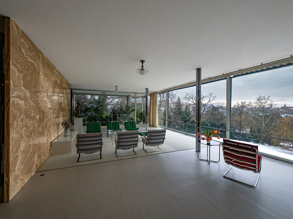 The main living room of Villa Tugendhat: the honey-gold onyx wall on the left, the full-height glass wall to the garden on the right